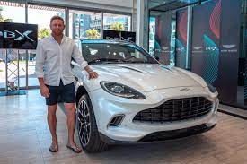 Johnny Bairstow stood outside a white Aston Martin DBX