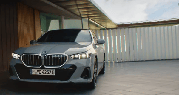 Silver BMW parked in a front drive with white fence in the background