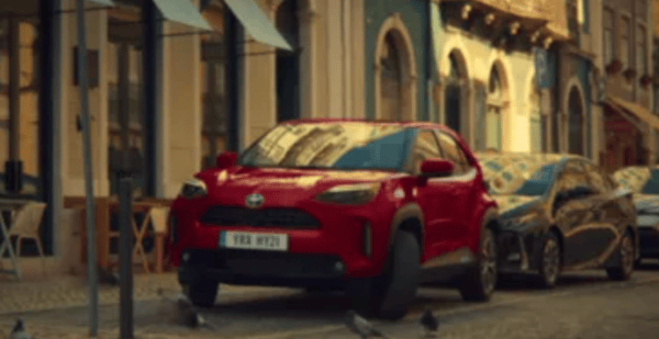 Red Toyota parked in a busy cobbled street