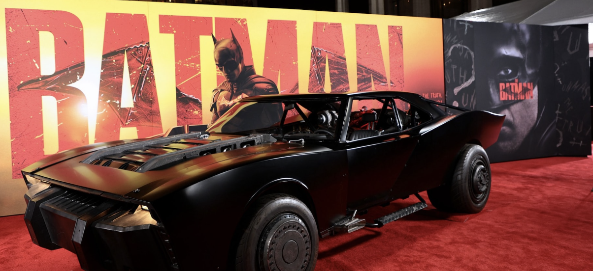 Batmobile from "The Batman" movie parked in front of promotional signage