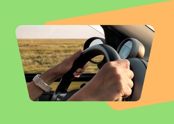 Person driving a car with their hands on the steering wheel
