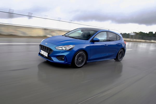 Blue Ford Focus Wagon driving along a wet road
