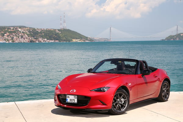 Red Mazda MX set to the backdrop of the ocean