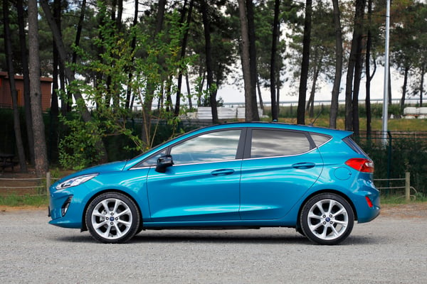Blue Ford Fiesta parked in front of some trees